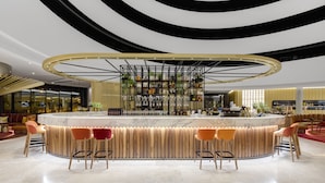 A modern bar area with a circular bar, multiple seating options, and a unique ceiling design.