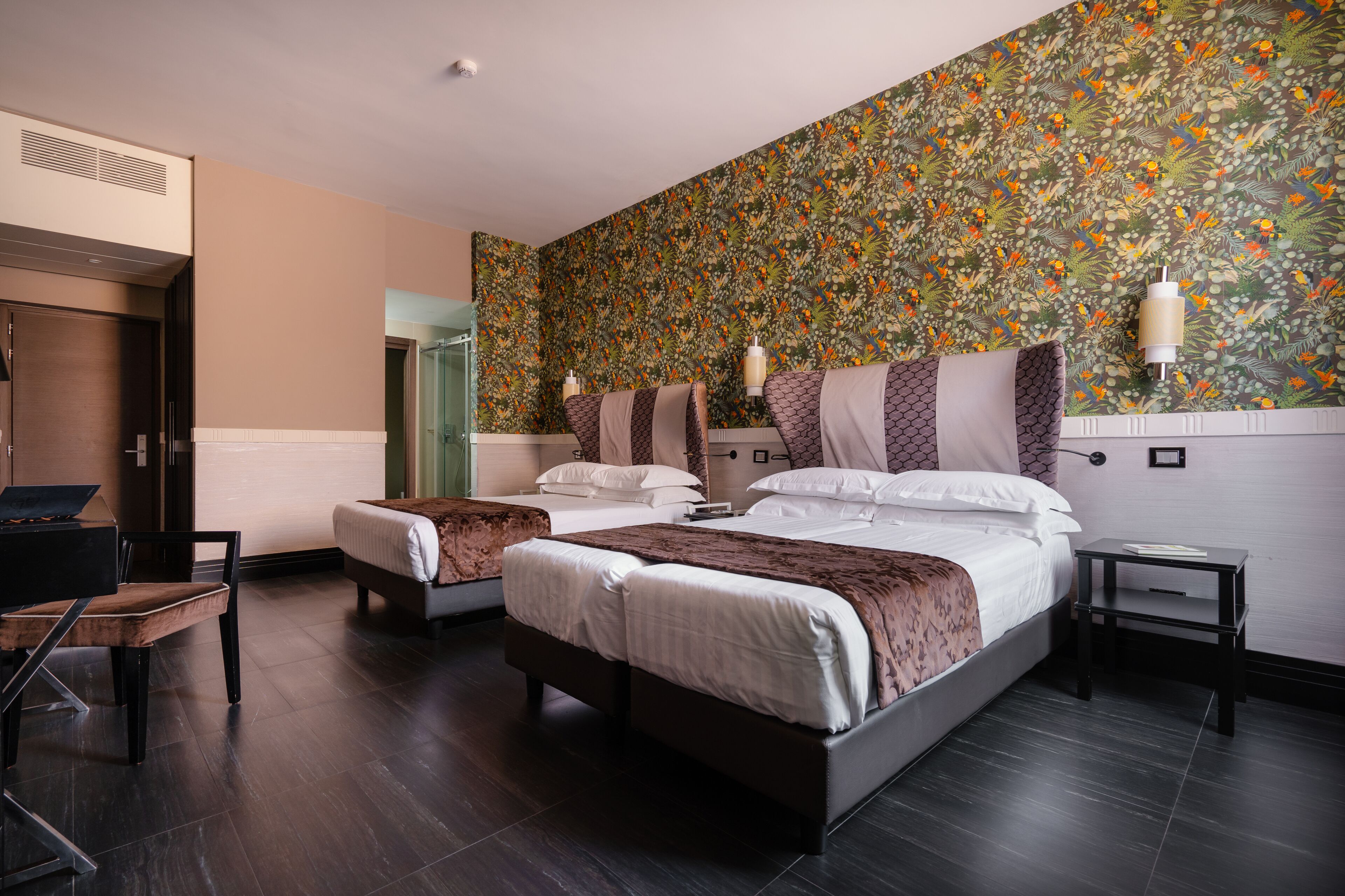 A hotel room with two beds, a desk, and a chair.