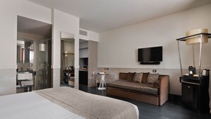 A modern hotel room with a large bed, a sofa, a TV, and a coffee machine. - Unica Suites Rome (Rome)
