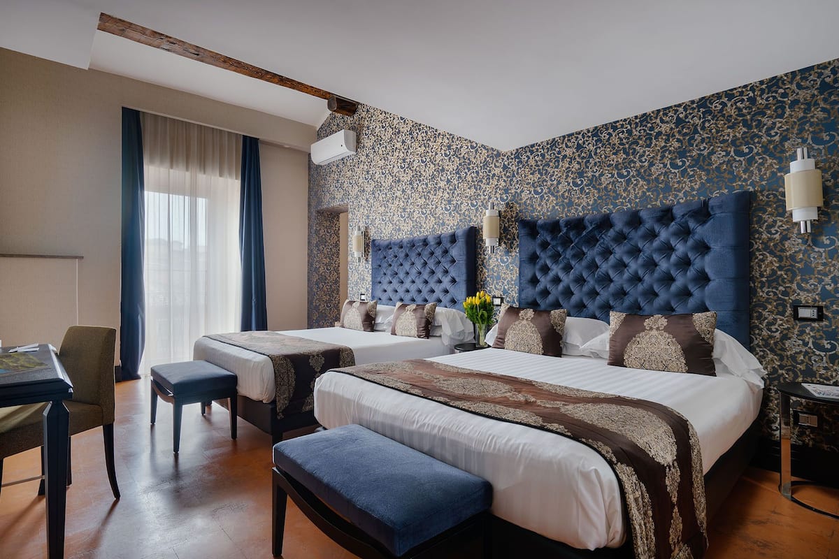 A hotel room with two beds, a desk, and a chair.