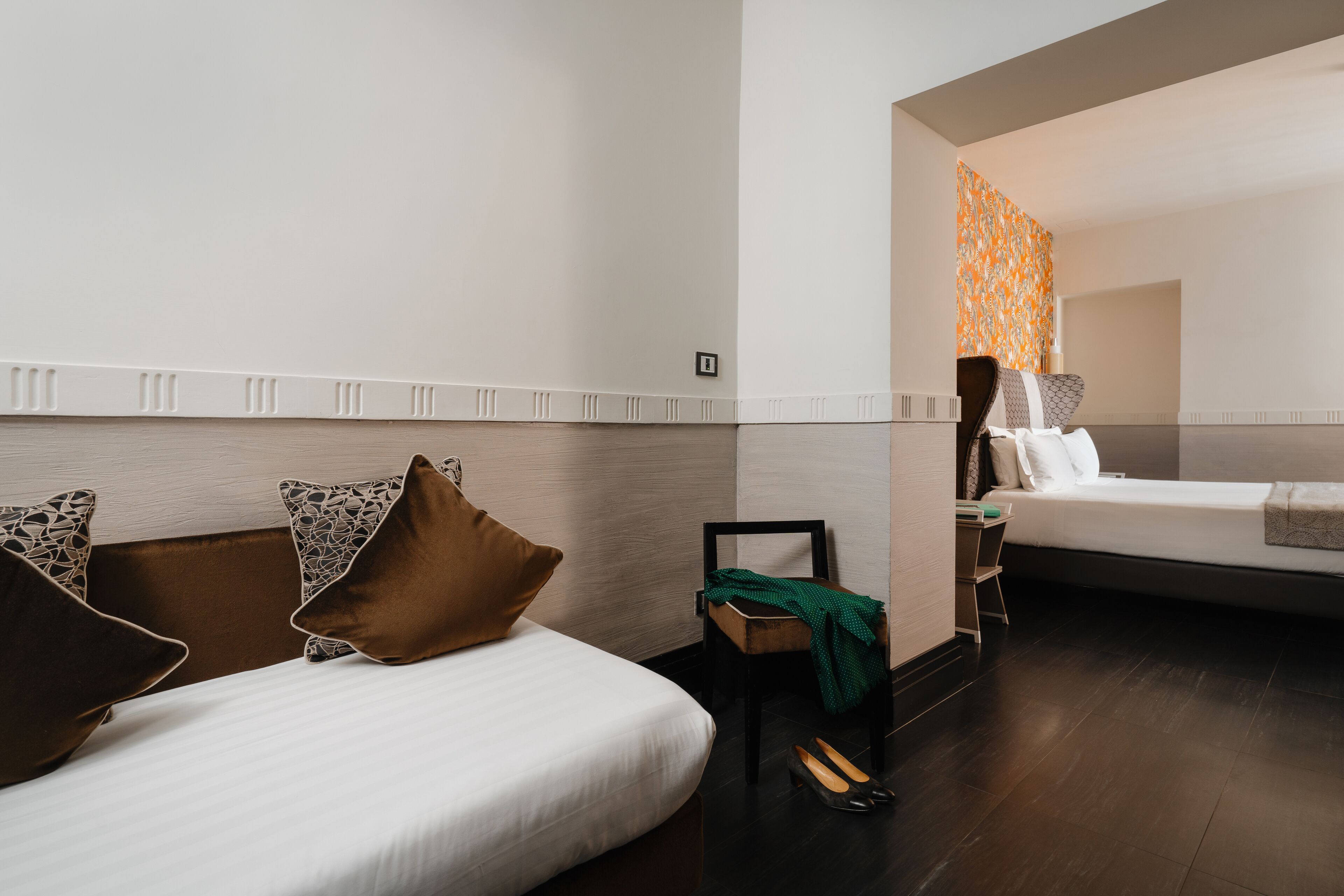 A hotel room with two beds, a chair, and a small table.