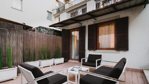 An outdoor patio with white metal furniture, including two sofas and a table. - Unica Suites Rome (Rome)