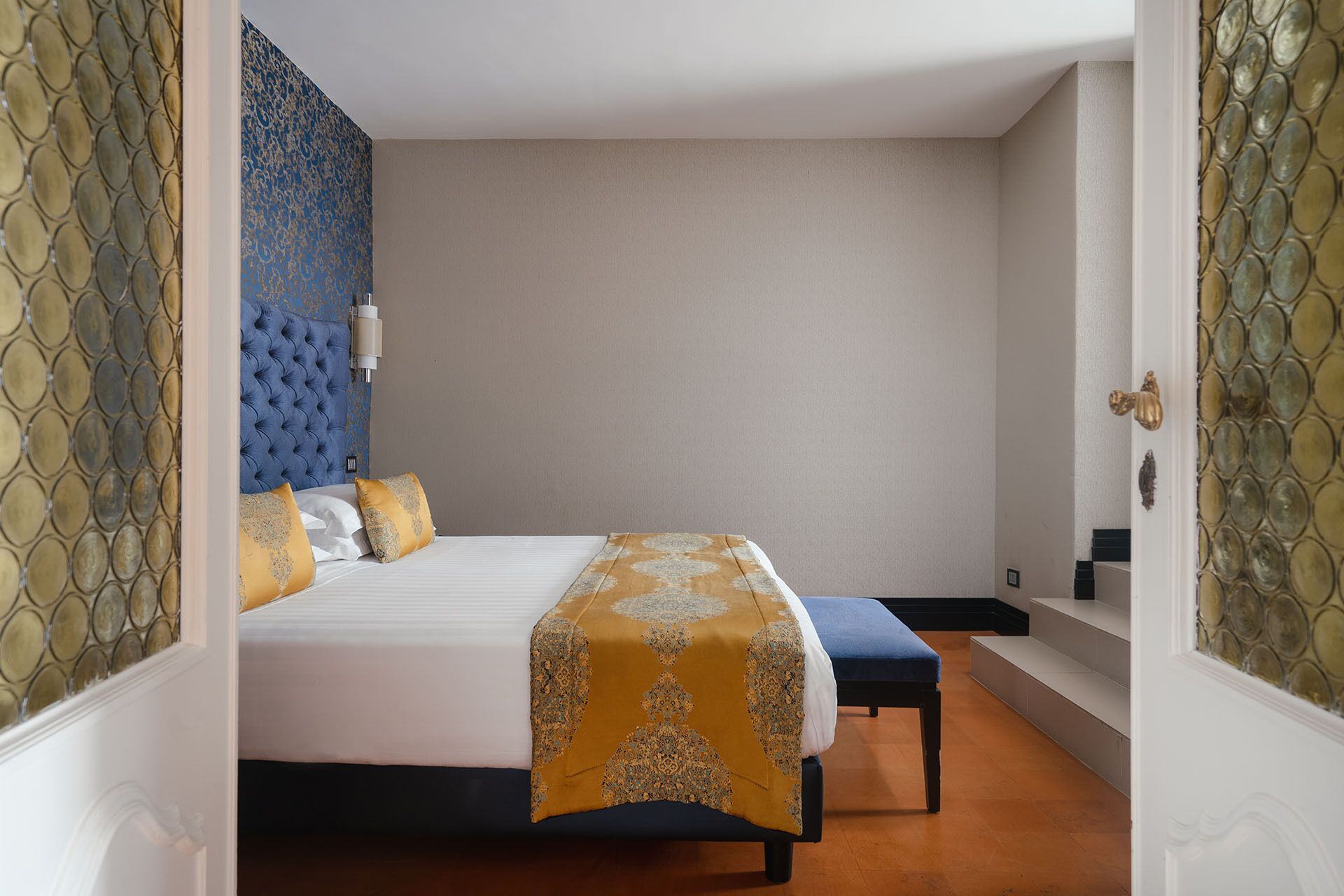 A bedroom with a bed, a bench, and a wall with a decorative pattern.