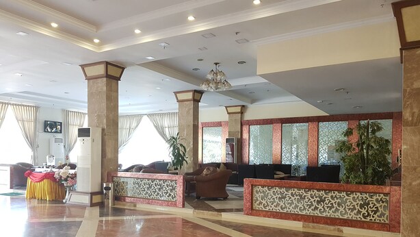 Un hall d’entrée spacieux doté d’un sol en marbre, d’un comptoir d’accueil, de coins salon et de colonnes décoratives.