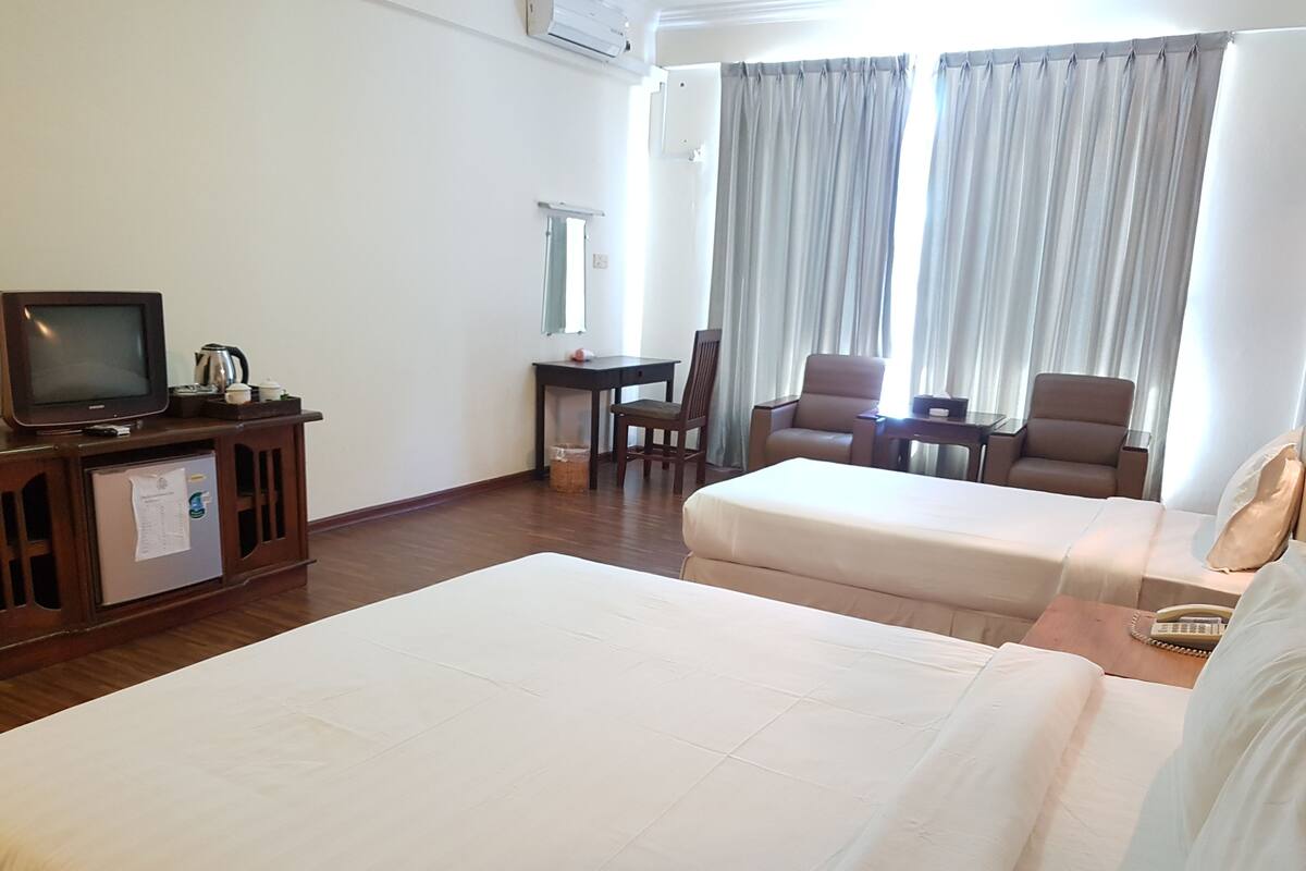 Une chambre d’hôtel avec deux lits, une télévision, un bureau et une chaise.