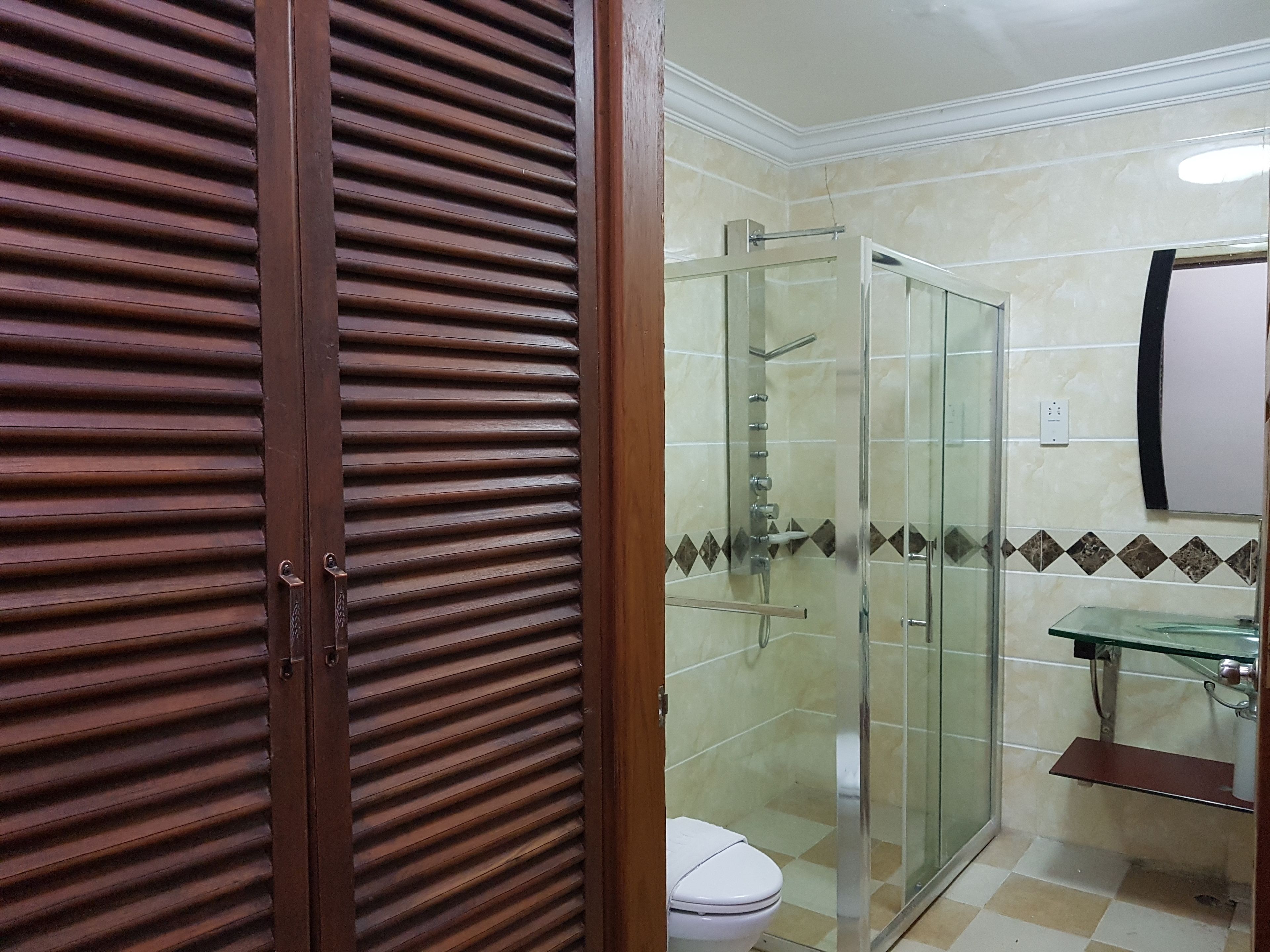 A bathroom with a glass shower enclosure, a toilet, and a sink with a glass countertop.