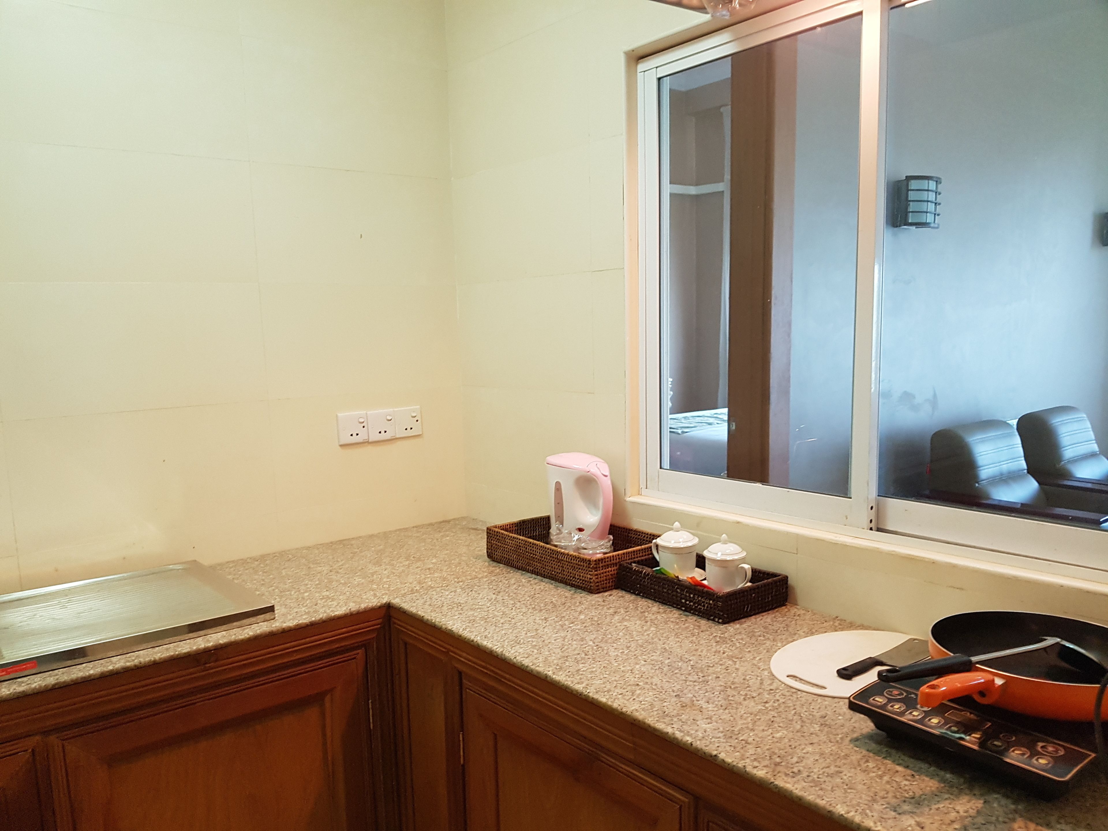 A kitchen with a granite countertop, a toaster, a kettle, and a frying pan.