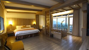 Une chambre d’hôtel avec un grand lit, un coin salon, un balcon avec vue et des boiseries.