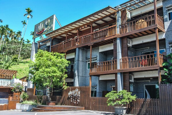 A multi-story hotel with balconies, a wooden fence, and a signboard. - Moon Water Resort (Yuli)