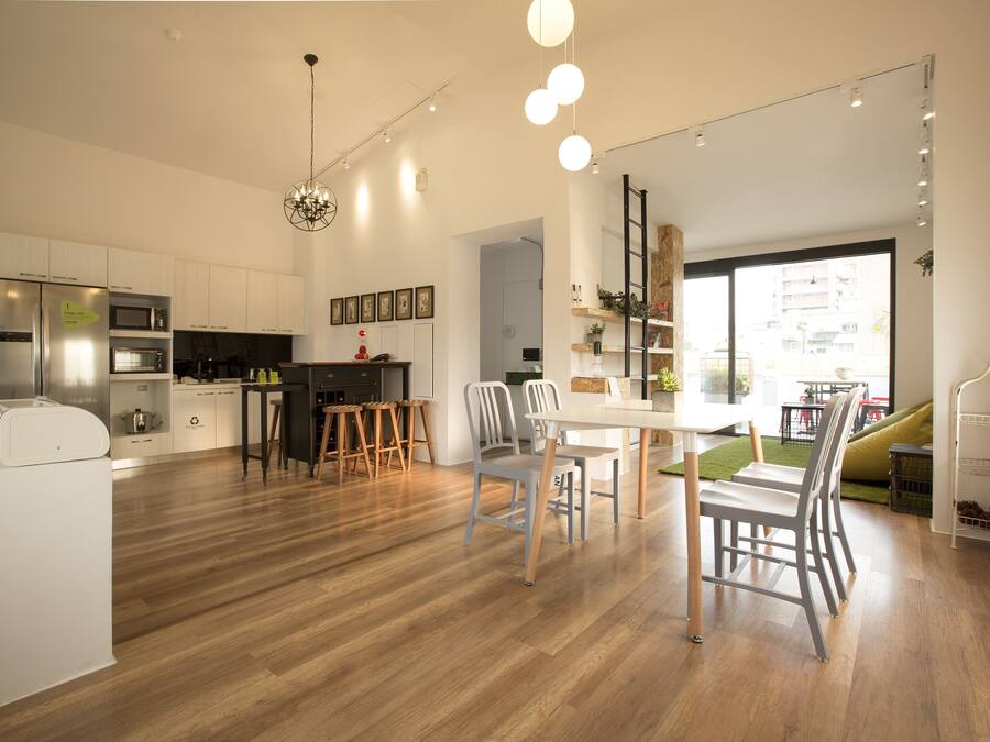 A modern kitchen with white cabinetry, a dining area with a white table and chairs, and a large window providing a view of the city.