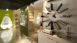 Een moderne hotellobby met een receptiebalie, een klok en een groene wand met uitzicht door een raam.