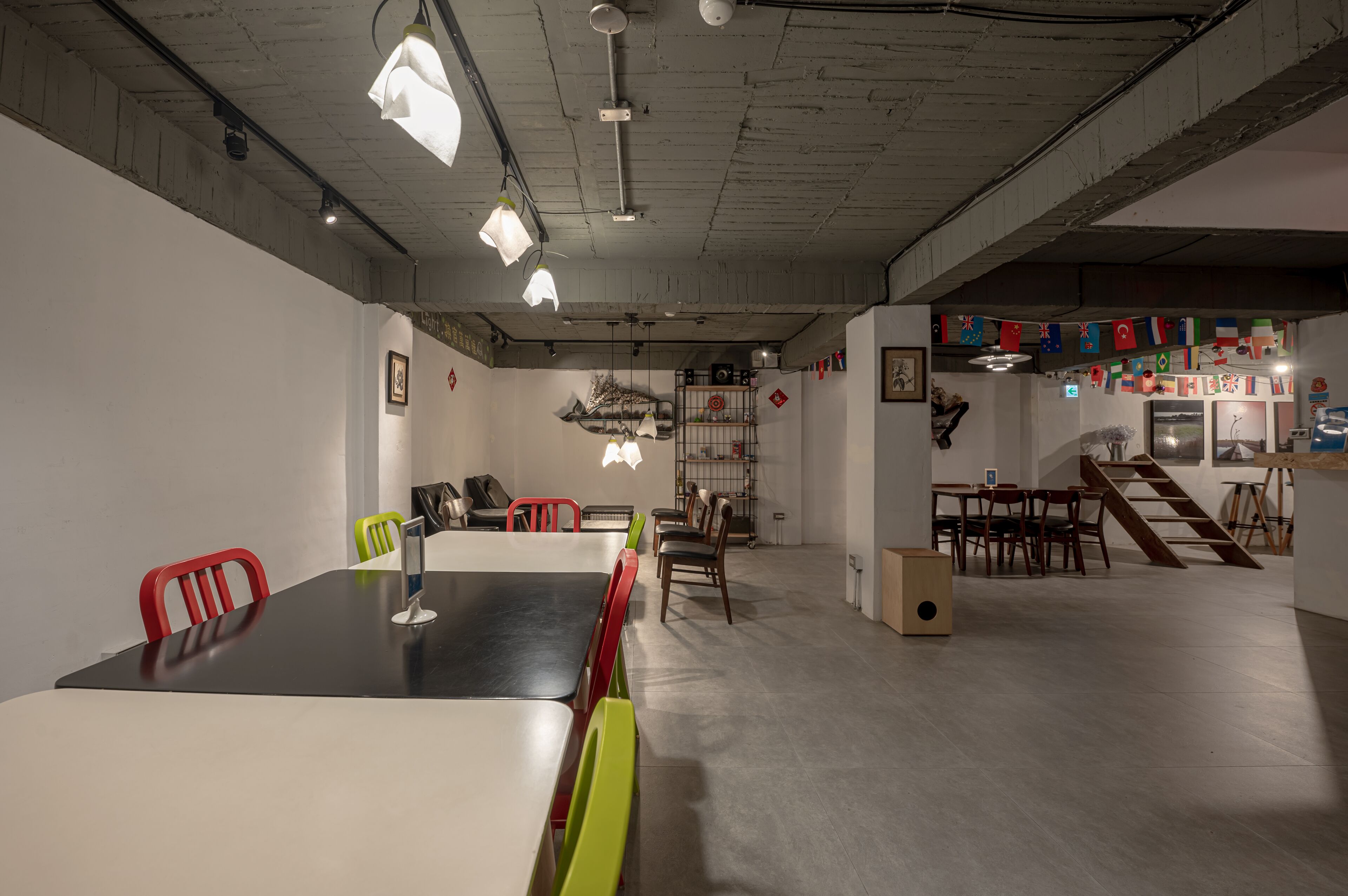 A spacious room with a long table and chairs, a staircase, and a shelf with various items.