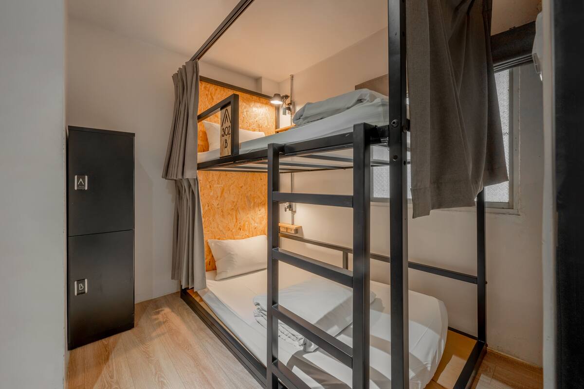 A bunk bed room with a wooden floor, a wardrobe, and a lamp.