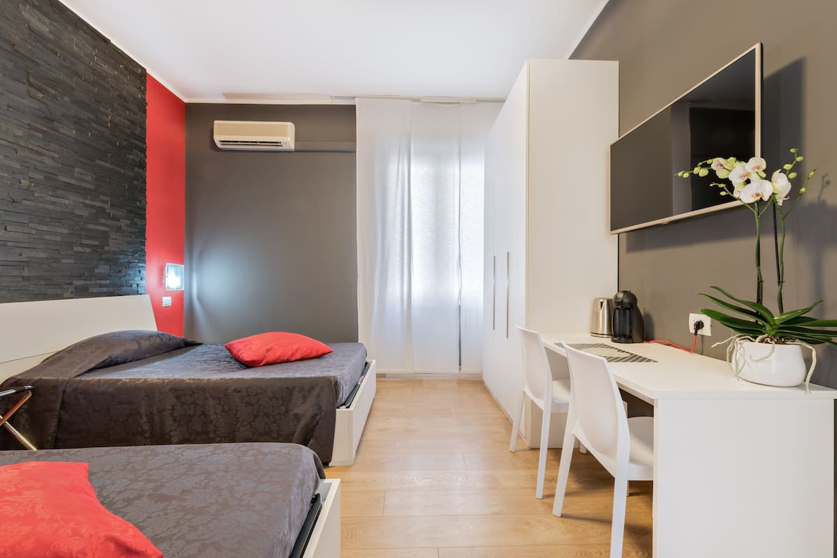 Une chambre moderne avec deux lits, un bureau et un grand miroir.