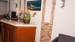Una cocina con encimera de mármol, armarios de madera, una planta en maceta, un televisor empotrado y una pared decorativa de ladrillo.