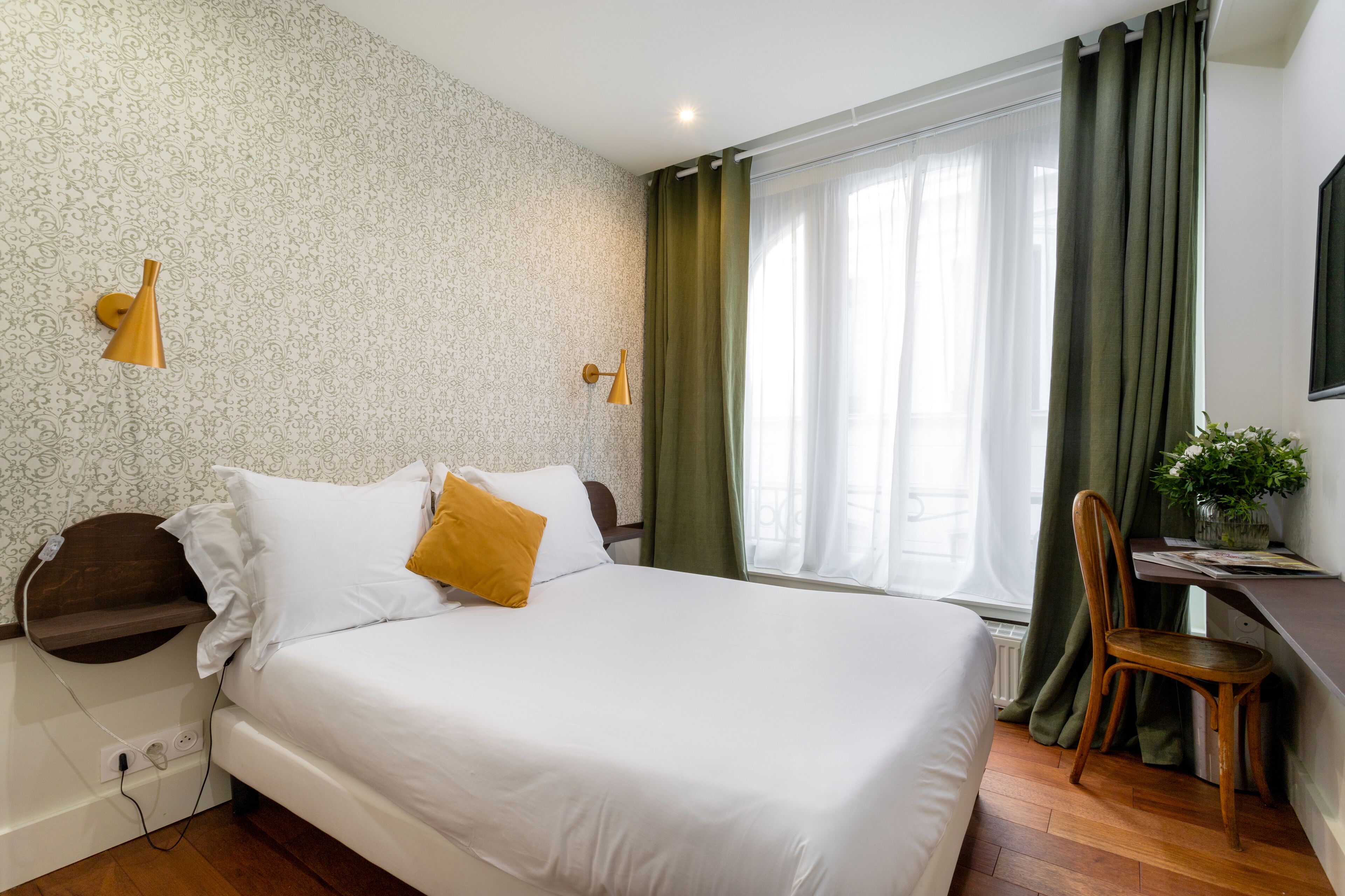 Une chambre bien rangée, avec un lit, une table de chevet, une lampe et un bureau avec une chaise.