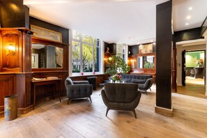 Une pièce spacieuse dotée de planchers en bois, d’une grande fenêtre et d’un coin salon comprenant deux fauteuils et une table.