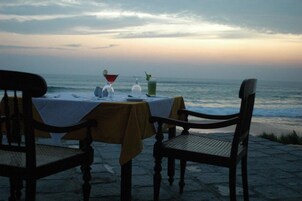 A table set with a white tablecloth, a glass of water, a cocktail glass, and a glass with a straw.