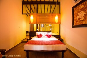 A hotel room with a large bed, two bedside tables, a nightstand, and a mirror above the bed.