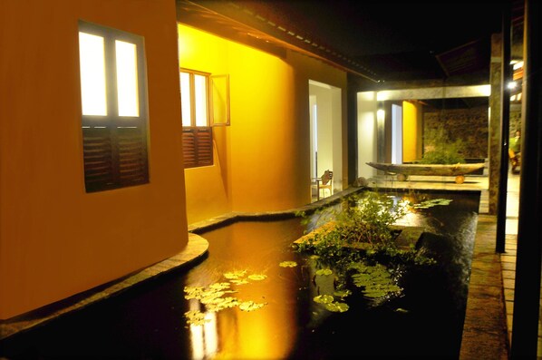 A dimly lit corridor with a water feature and a stone bench. - The Beach Cabanas (Koggala)