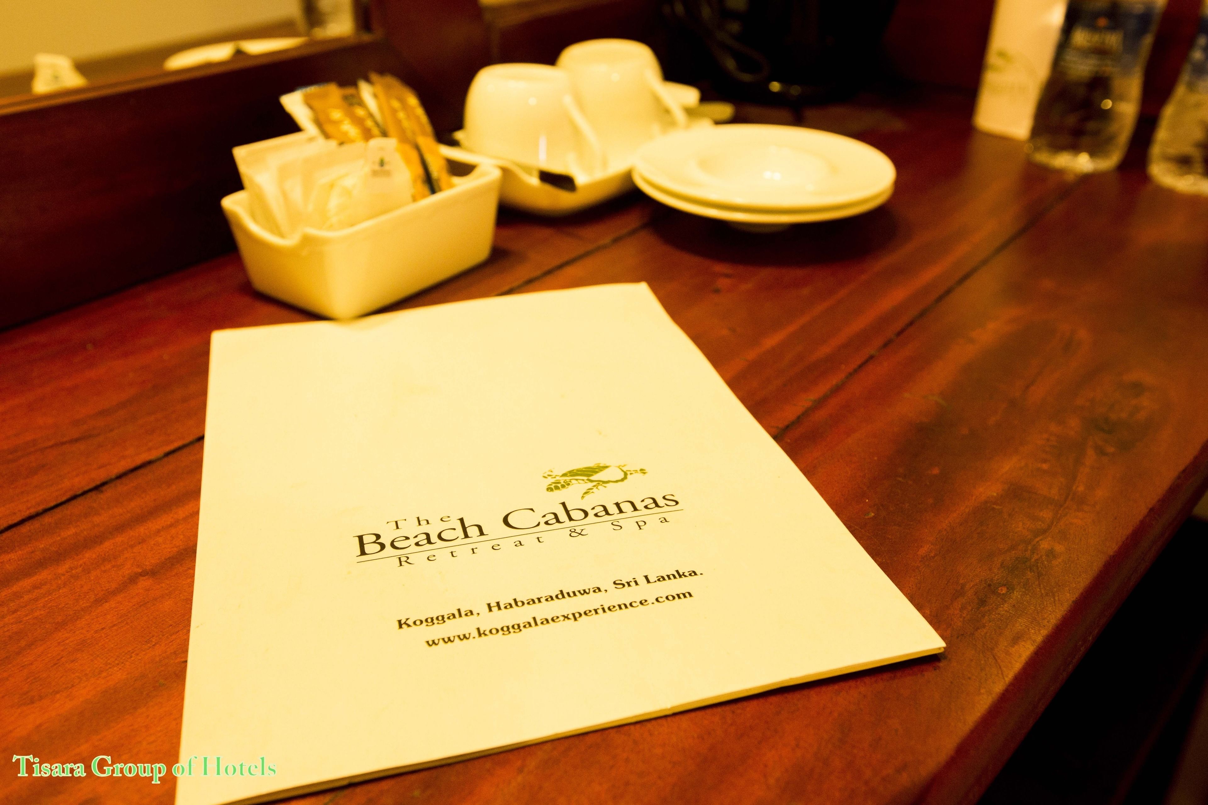 A menu on a wooden table with a bowl of bread and a plate.