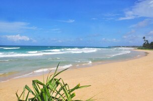 A beach with clear blue water and a sandy shore.