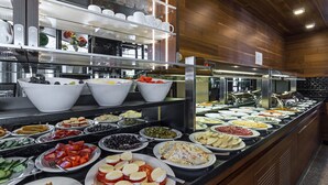 Un bufé con diferentes opciones de comida, incluyendo frutas, quesos y ensaladas.