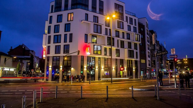Un edificio moderno de varios pisos con grandes ventanales y una entrada destacada.