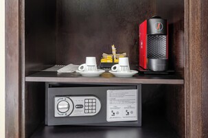 Una macchina per il caffè, due tazze bianche e un vassoio con capsule di caffè su un ripiano di legno.