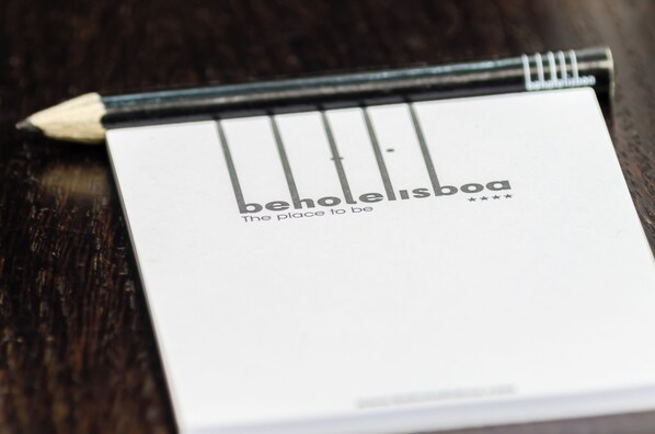 A notebook with the text "behotelisboa" and "The place to be" on a dark wooden surface. - Behotelisboa (Lisbon)