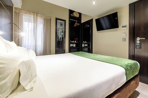 A hotel room with a large bed, a television mounted on the wall, and a wardrobe with a mirror.
