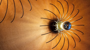 A light fixture with a spherical bulb and multiple curved arms on a textured surface.