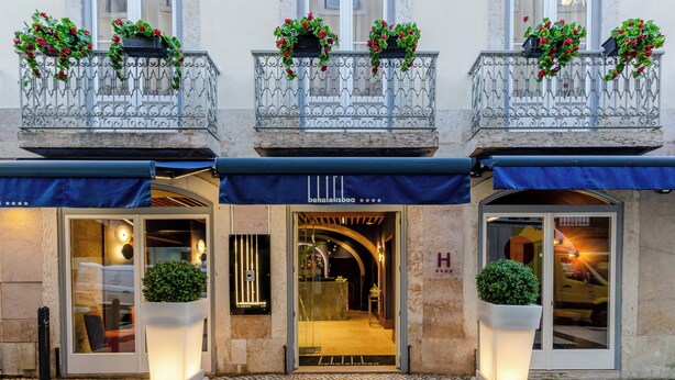 A hotel entrance with a glass door, a reception desk, and potted plants. - Behotelisboa (Lisbon)