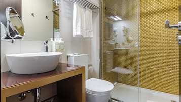 A bathroom with a large white sink, a toilet, a glass shower enclosure, and a mirror.