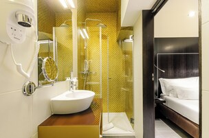 A bathroom with a white sink, a mirror, a hairdryer, and a shower.