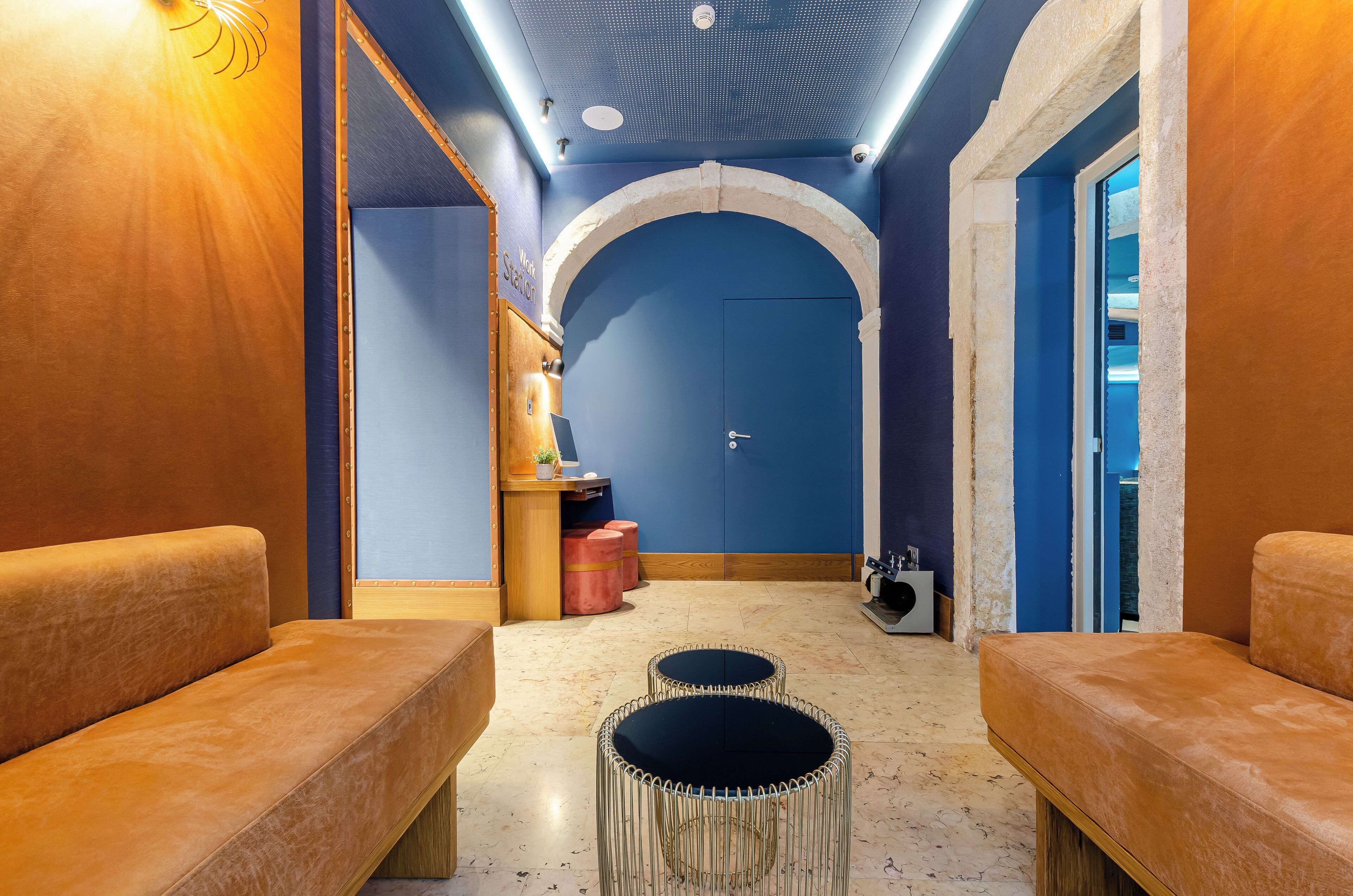 A spa room with a blue wall, wooden benches, a massage table, and a massage chair.