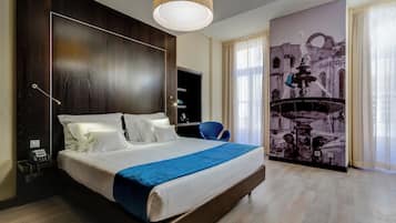 A hotel room with a large bed, a desk with a telephone, and a wall-mounted TV.