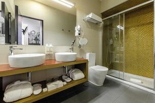 Une salle de bain moderne avec deux lavabos, des toilettes, une douche en verre et un meuble-lavabo agrémenté de serviettes et d’articles de toilette.
