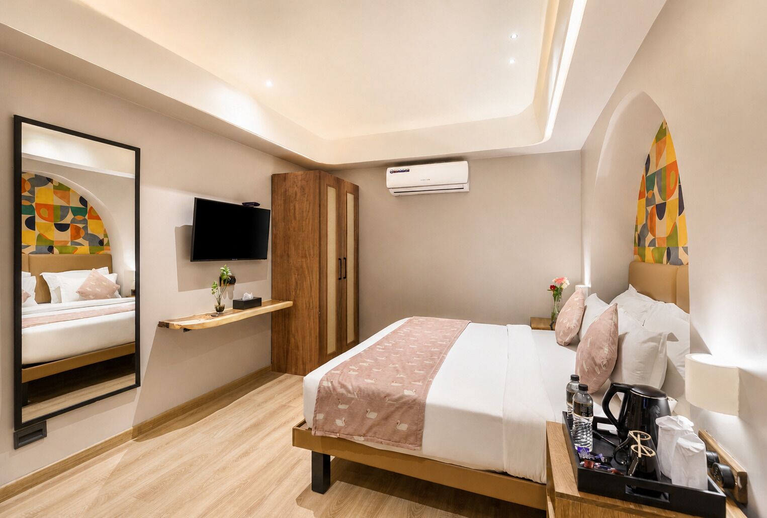 Une chambre d’hôtel moderne équipée d’un lit, d’une télévision, d’une armoire et d’une petite table avec des commodités.