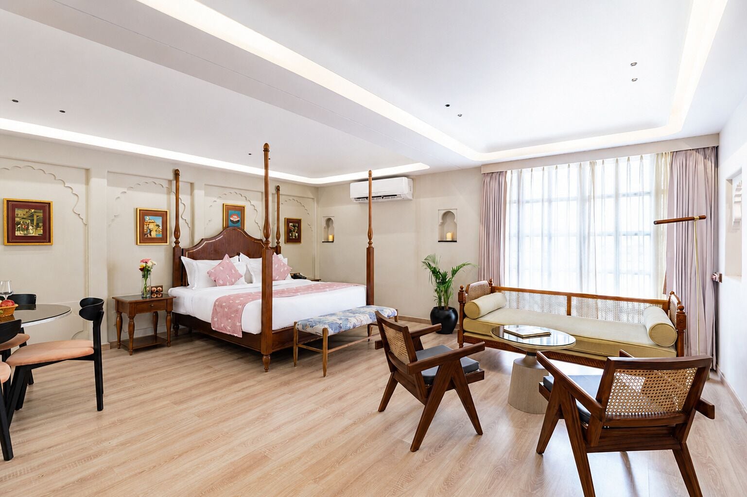 Una habitación de hotel con una cama con dosel, un sofá, una mesa de comedor y una silla.