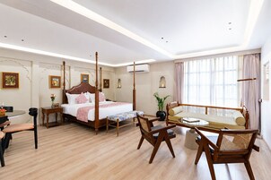 Una habitación de hotel con una cama con dosel, un sofá, una mesa de comedor y una silla.