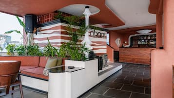 A bar area with a sofa, potted plants, and a bar counter.
