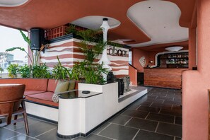 Una zona de bar con sofá, plantas en macetas y barra.