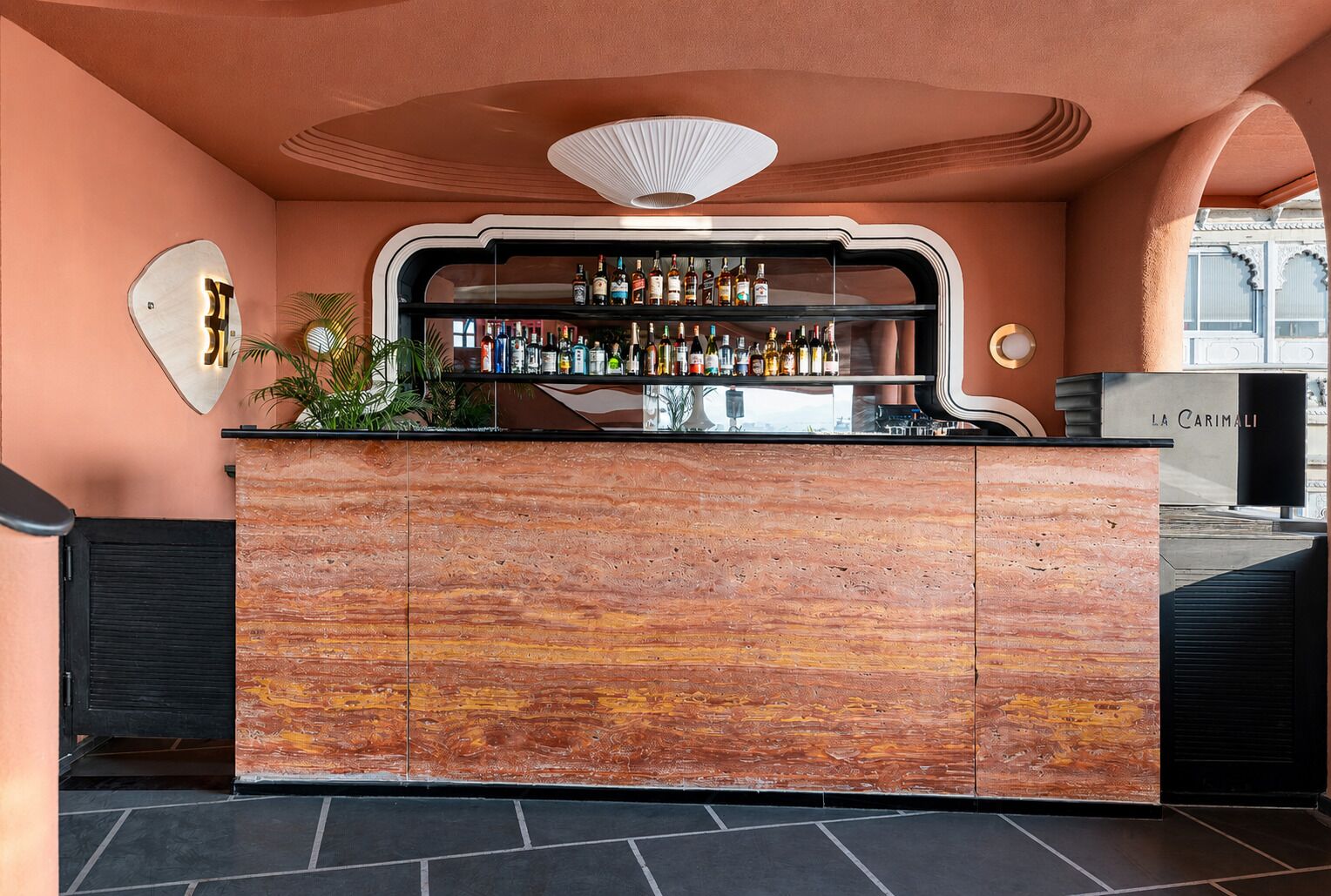 A bar area with a wooden counter and a variety of bottles.