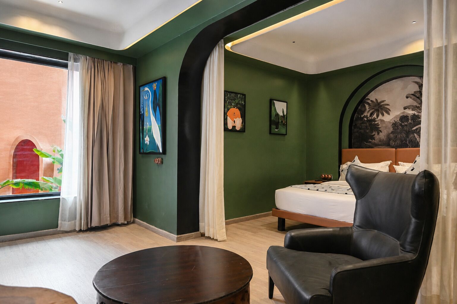 Ein Hotelzimmer mit Bett, Stuhl, kleinem Tisch und Bildern an den Wänden.