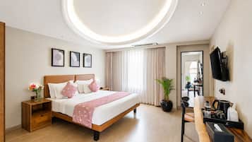 Una habitación de hotel moderna con cama, mesita de noche, planta en maceta y un escritorio con silla.