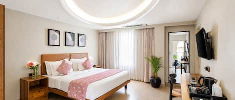 Una habitación de hotel moderna con cama, mesita de noche, planta en maceta y un escritorio con silla.