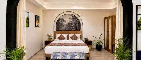 A bedroom with a bed, a headboard with a mural, bedside tables, and potted plants.