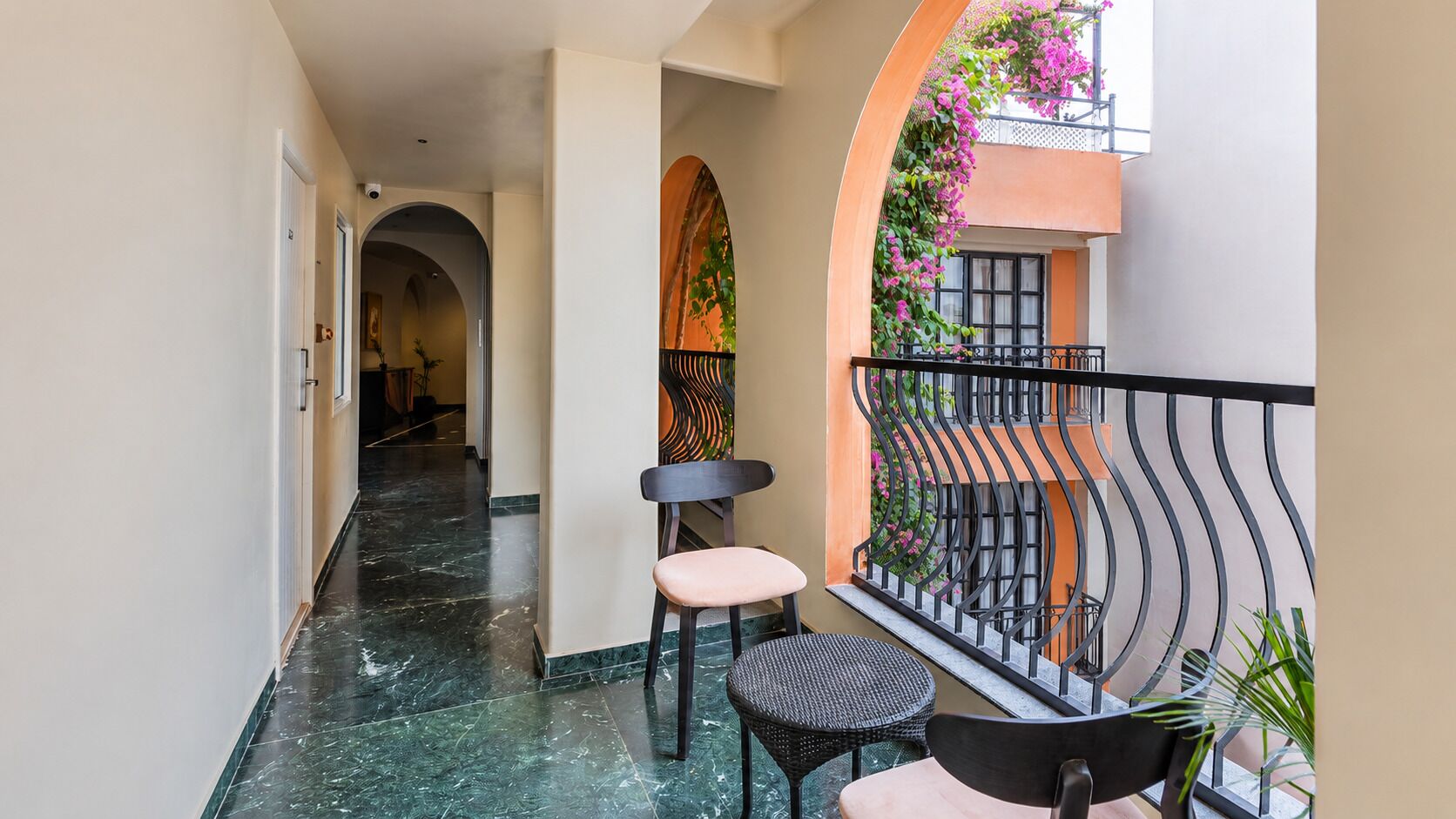 A corridor with a marble floor, a chair, and a small table.