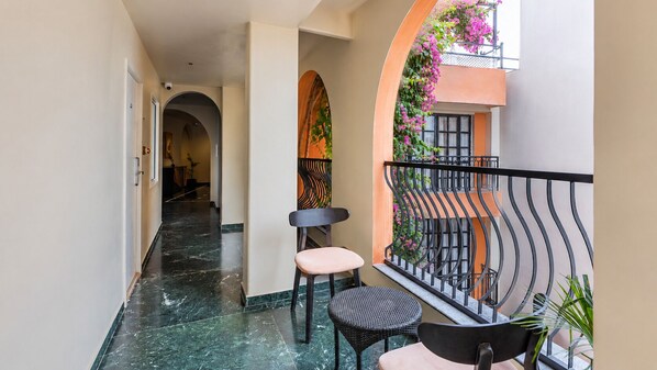 A corridor with a marble floor, a chair, and a small table.